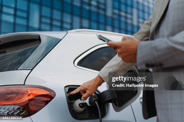 close-up of businessman charging his car. - wireless charging stock-fotos und bilder