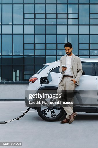 Young multiracial man waiting for car charging. Young multiracial man waiting for car charging.