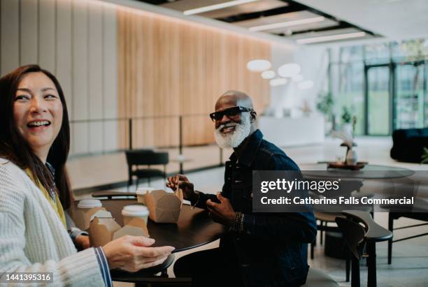 candid image of a man and woman enjoying a takeaway lunch together - lunch break stock pictures, royalty-free photos & images