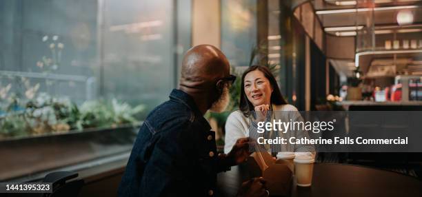 cinematic image of a man and a woman sitting at a table in a cafe - enterprise stock pictures, royalty-free photos & images