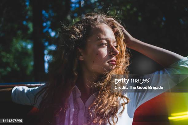 female teenager with hand in hair on sunny day - postureo fotografías e imágenes de stock