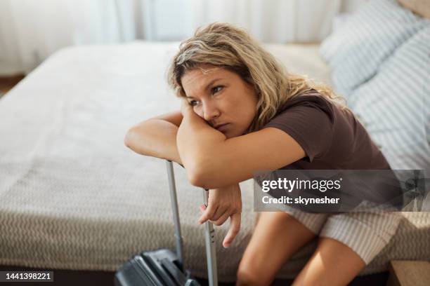 mujer triste soñando despierta después de llegar a una habitación de hotel de su viaje. - woman day dreaming fotografías e imágenes de stock