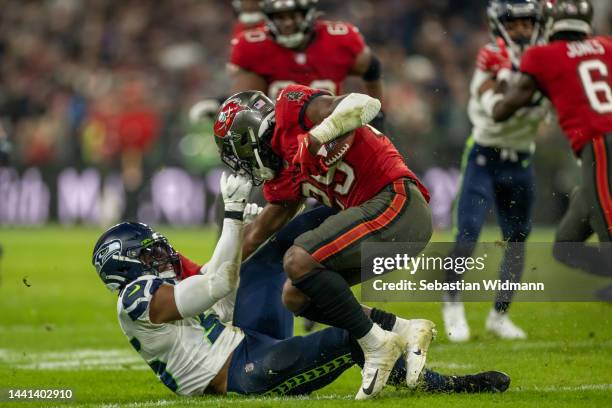 Jordyn Brooks of the Seattle Seahawks is fended off by Rachaad White of the Tampa Bay Buccaneers in the third quarter during the NFL match between...