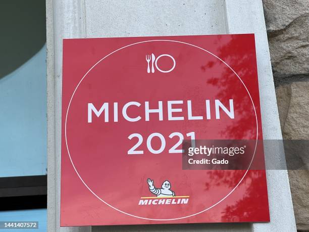 Eye-level shot of a red, white, and yellow 'Michelin 2021' logo, with fork, knife, and plate symbols and a waving Bibendum , attached to an exterior...