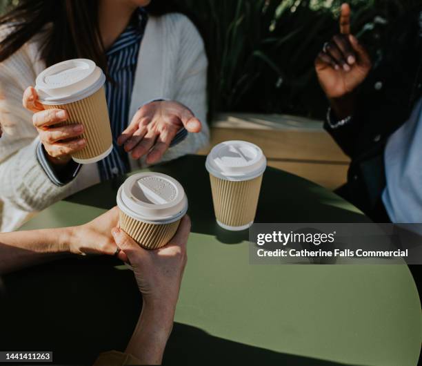 a group of colleagues sit at a table outdoors and enjoy some takeaway coffees - heißgetränk gefäß stock-fotos und bilder