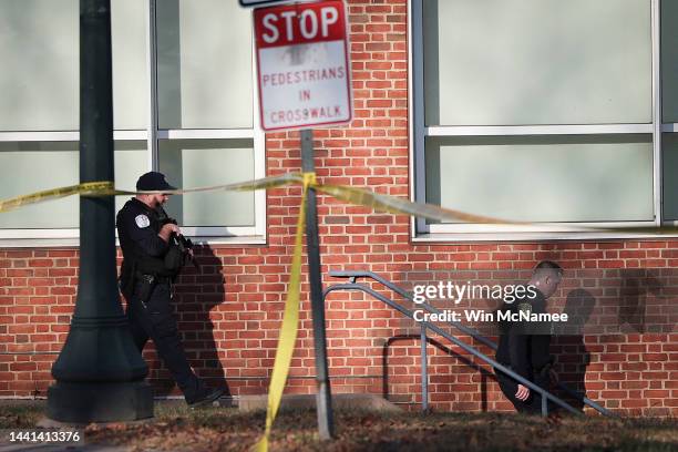 Law enforcement personnel move through the crime scene where 3 people were killed and 2 others wounded on the grounds of the University of Virginia...