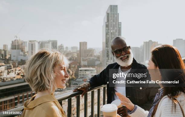 three people stand on a rooftop / balcony in a city - luxury city break stock pictures, royalty-free photos & images