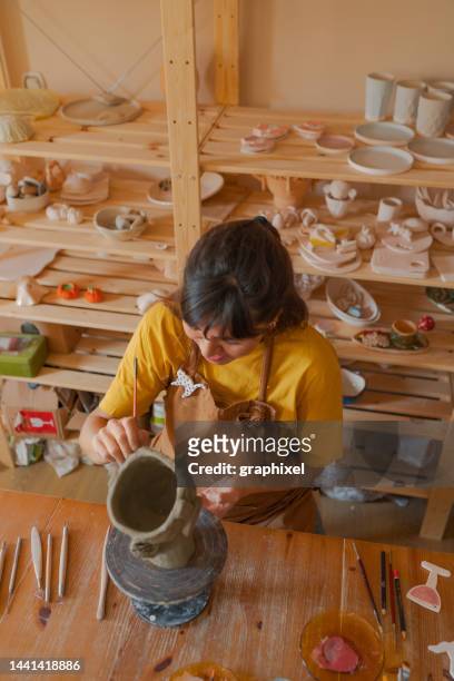 jeune femme fabriquant un vase en poterie avec de l’argile dans son atelier - sculpteur photos et images de collection