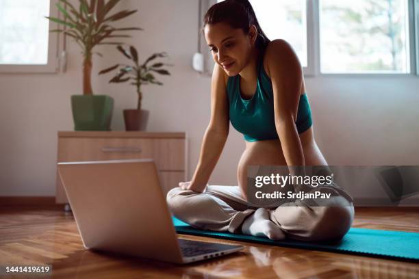 pregnant young woman having an online yoga class - prenatal care stockfoto's en -beelden