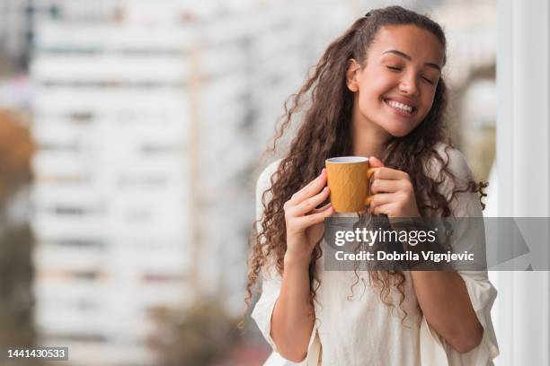mujer con los ojos cerrados disfrutando de una taza de café - tomando cafe fotografías e imágenes de stock