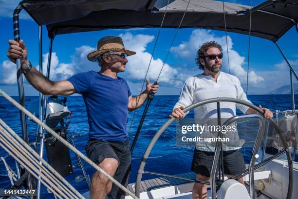 two adults using a sailboat in the aegean sea. - sailing greece stock pictures, royalty-free photos & images