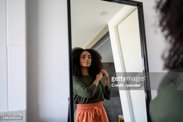 鏡の中の黒人女性が髪を見ている - black hair ストックフォトと画像