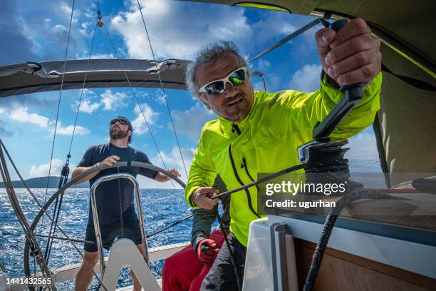 deux adultes et un adolescent utilisant un voilier dans la mer égée. - sailing greece photos et images de collection