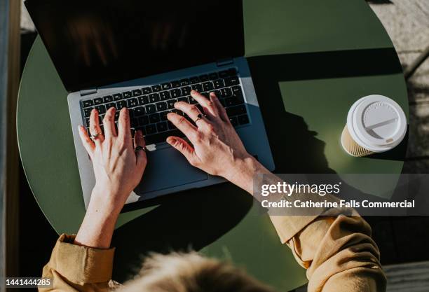 close-up of hands typing on a laptop computer - eficacia fotografías e imágenes de stock