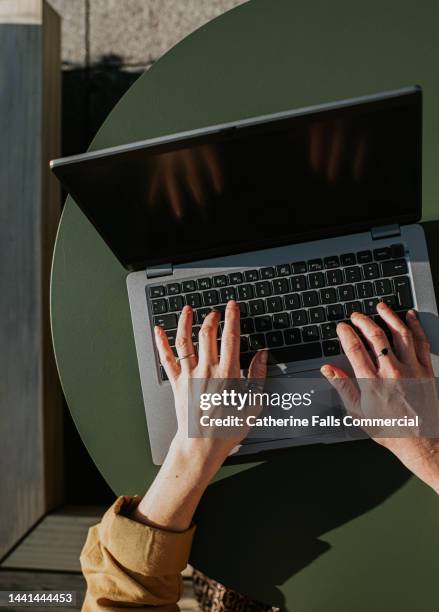 close-up of hands typing on a laptop computer - mitarbeiter büro tastatur stock-fotos und bilder