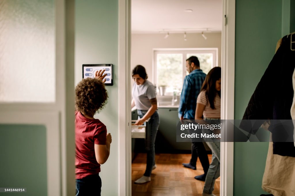 Boy using digital tablet while family in kitchen at home
