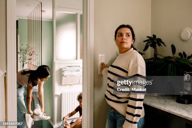 woman turning off light switch while standing near doorway at home - 止まる ストックフォトと画像