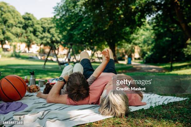 grandfather and grandson lying down on picnic blanket at park - child lying down stock pictures, royalty-free photos & images
