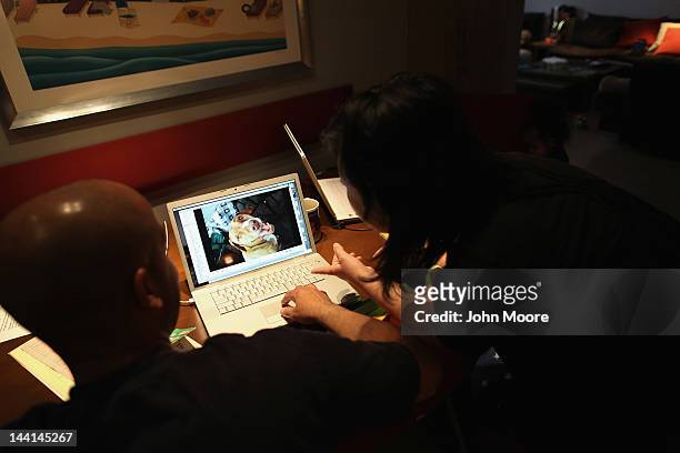 Pet owners Tiga , and Togo McLoyd look over photos of their dog Rocky after veterinarian Wendy McCulloch euthanized their pet on May 9, 2012 in New...
