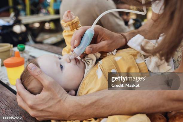 father cleaning nose of toddler daughter through nasal aspirator - tubo de succión fotografías e imágenes de stock