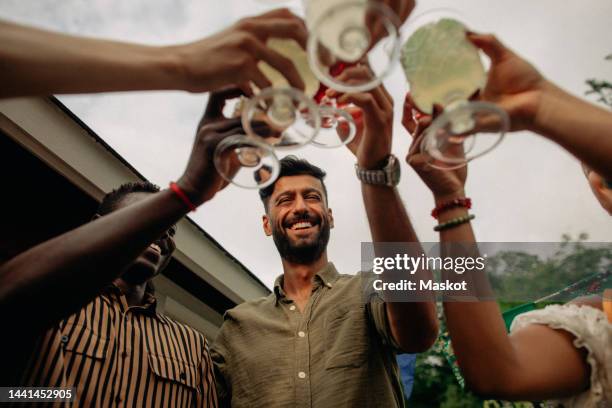 low angle view of happy multiracial friends toasting drinks at party - low alcohol drink stock pictures, royalty-free photos & images