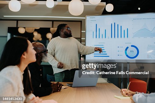 A man gives a presentation using a large television screen / monitor. A man gives a presentation using a large television screen / monitor.