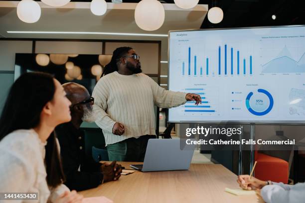 a man gives a presentation using a large television screen / monitor. - presenting data business stock-fotos und bilder