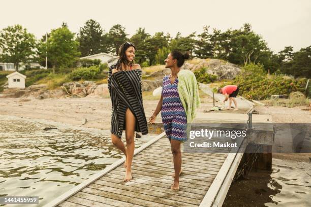 mother and daughter communicating with each other while walking on jetty during vacation - bathing jetty stock pictures, royalty-free photos & images