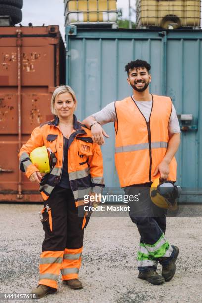 full length of smile male and female construction workers in reflective clothing standing at site - construction worker pose imagens e fotografias de stock