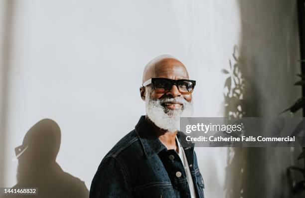 portrait of a confident older gentleman looking directly at the camera against a plain background - tinted eyeglasses stockfoto's en -beelden