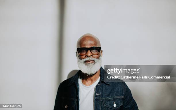 portrait of a confident older gentleman looking directly at the camera against a plain background - bald black man with beard stock pictures, royalty-free photos & images