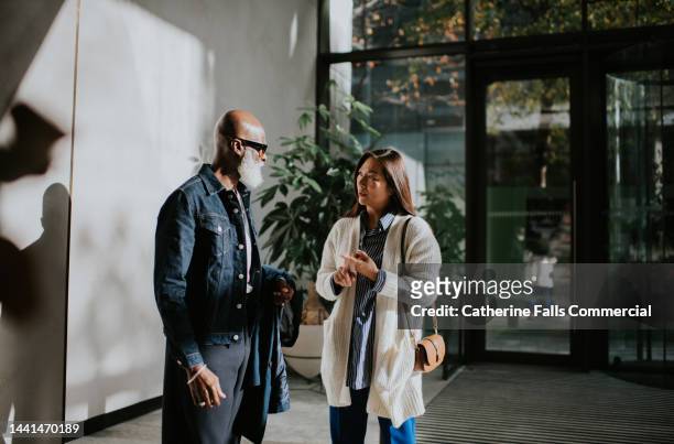 a man and a woman stand at the reception of a sunny commercial building - two point stock-fotos und bilder