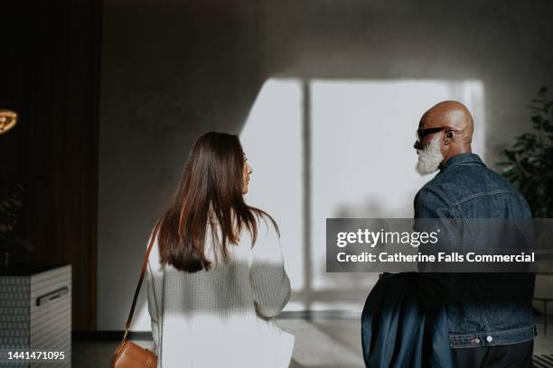 conceptual image of a man and a woman standing next to each other, and walking away from the camera. - divorce photos et images de collection
