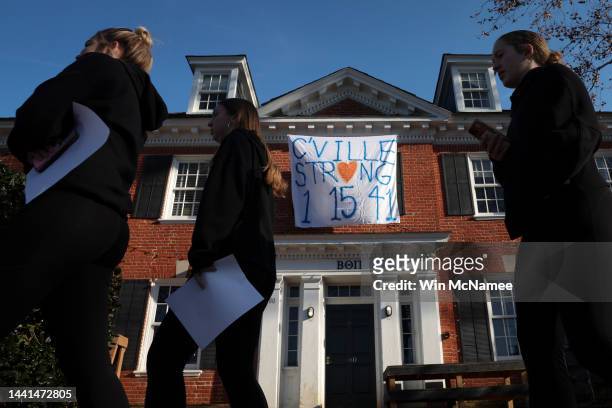 Students walk past a fraternity house with a banner memorializing three University of Virginia football players killed during an overnight shooting...