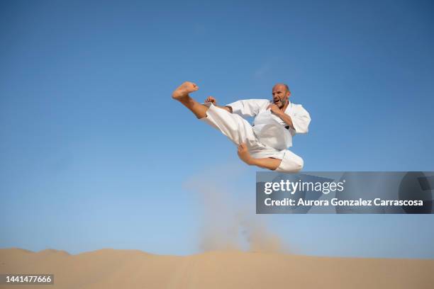 muscular man practicing karate in karate uniform and black belt. - judo stock-fotos und bilder