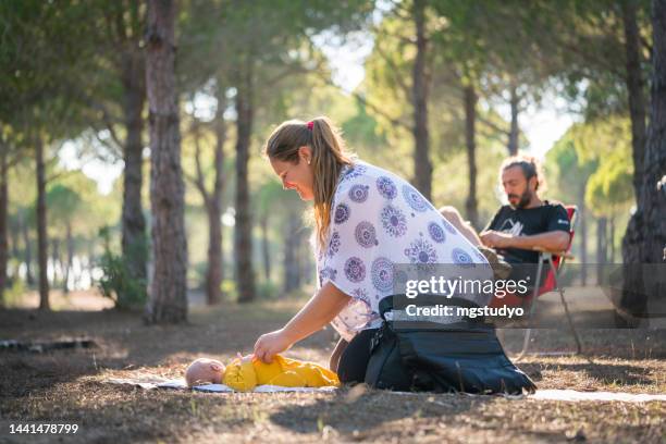 mother spends time with her newborn baby in the forest changing her diaper - nappy change stock pictures, royalty-free photos & images