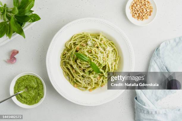 traditional italian pesto pasta spaghetti with pine nuts, garlic, basil, parmesan cheese. light gray table. homemade italian cuisine. vegetarian green pasta. - linguine photos et images de collection