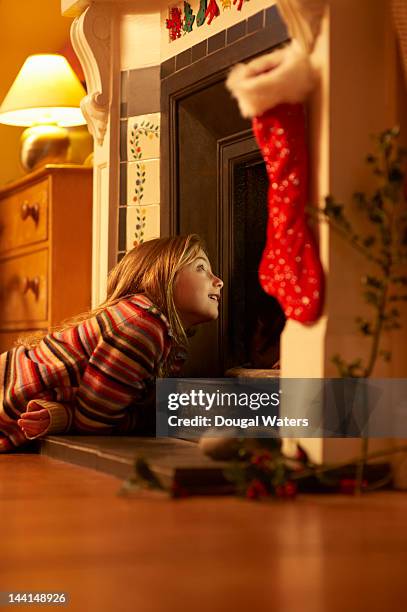 girl looking up chimney at christmas. - stocking tops stock-fotos und bilder