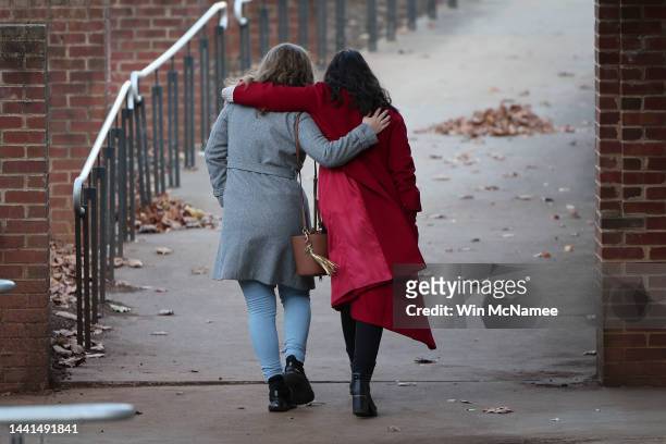 Two University of Virginia students walk away after placing flowers outside Scott Stadium at a makeshift memorial for three University of Virginia...
