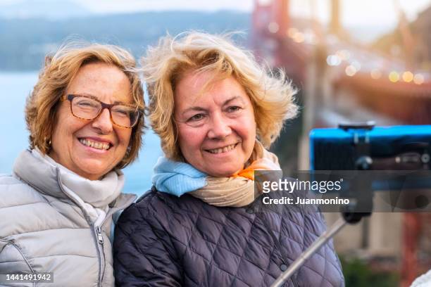 smiling happy mature senior lesbian in a honeymoon journey taking a selfie - only mature women stock pictures, royalty-free photos & images