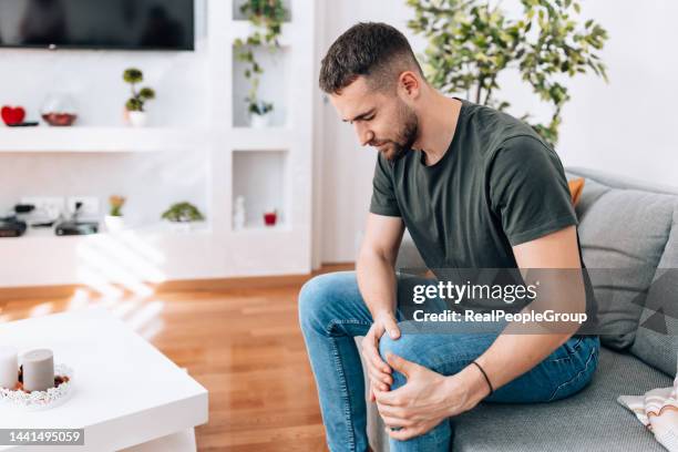 wounded young man holding his knee - male knee stock pictures, royalty-free photos & images