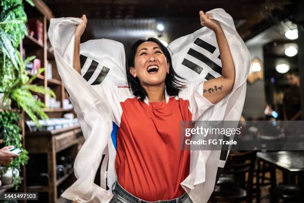 バーで韓国の国旗で祝う成熟した女性 - asian flags ストックフォトと画像