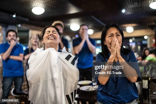 group of friends disappointed while rooting for their team at bar - cross channel stock pictures, royalty-free photos & images