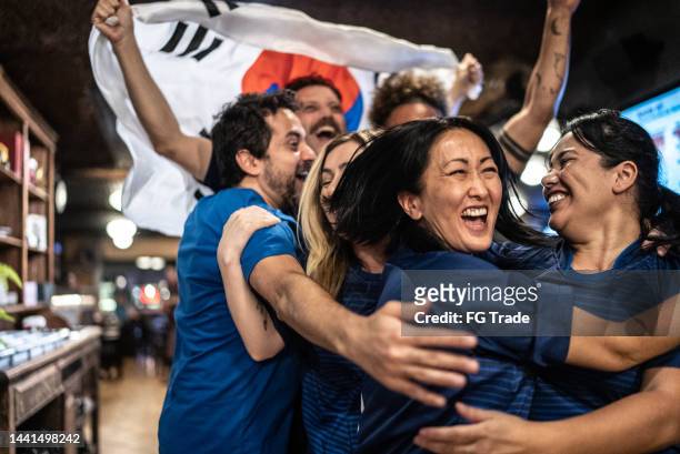 friends rooting for south korean team and celebrating at bar - international team soccer stock pictures, royalty-free photos & images