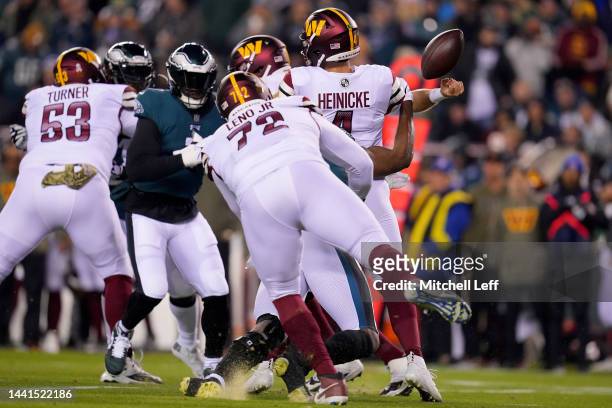 Taylor Heinicke of the Washington Commanders gets sacked and fumbles the ball against Josh Sweat of the Philadelphia Eagles during the first quarter...