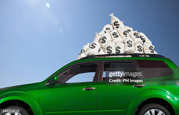 $ money bags piled on car roof - car money stock-fotos und bilder