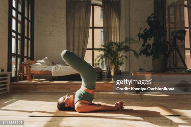 side view of asian woman wearing green sportwear doing yoga exercise,yoga child s pose or balasana,calm of healthy young woman breathing and meditation with yoga at home,exercise for wellness life - mudra stock-fotos und bilder
