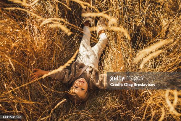 cute baby girl lying in grass, smiling and having fun. happy childhood. overhead view. - baby lachen natur stock-fotos und bilder