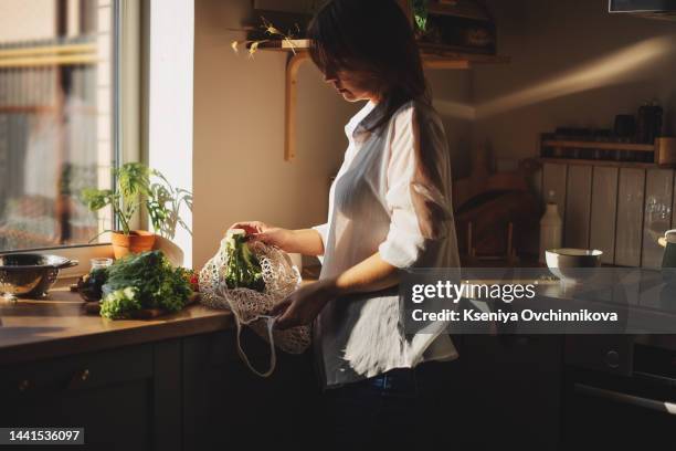 shopping bag with raw vegetables and fruits held by young woman in casualwear - hausfrau stock-fotos und bilder