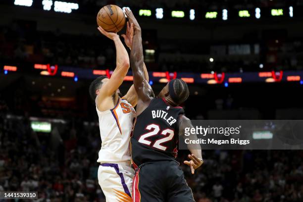 Jimmy Butler of the Miami Heat blocks a shot by Devin Booker of the Phoenix Suns during the fourth quarter at FTX Arena on November 14, 2022 in...
